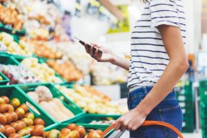 Woman using phone while buying groceries
